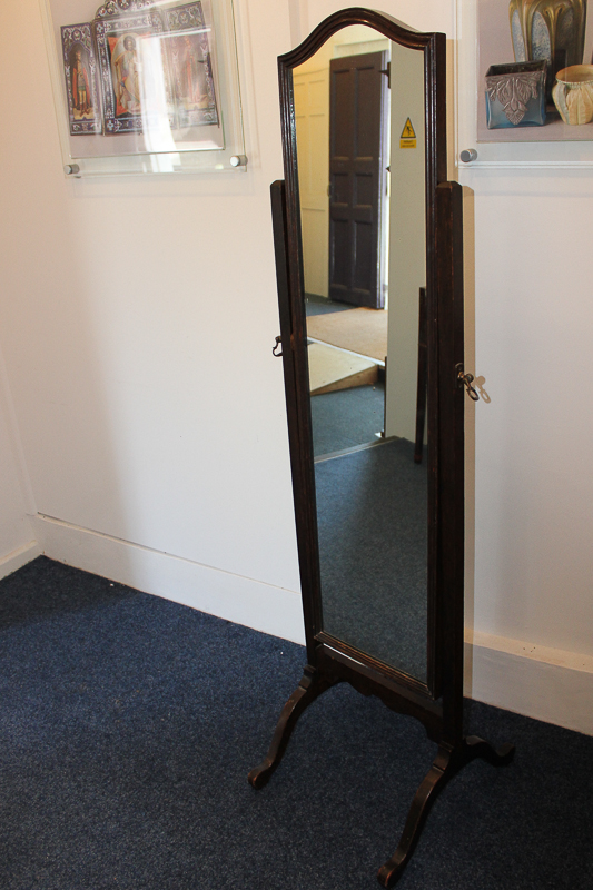 A dark oak framed cheval mirror with shield shaped top, on four curved legs, 47cm