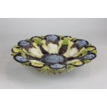 A 19th century Castle Hedingham pottery dish of scalloped form with applied decoration of urns,