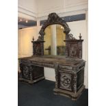 A large Victorian carved oak pedestal sideboard with mirror back and panels carved with game