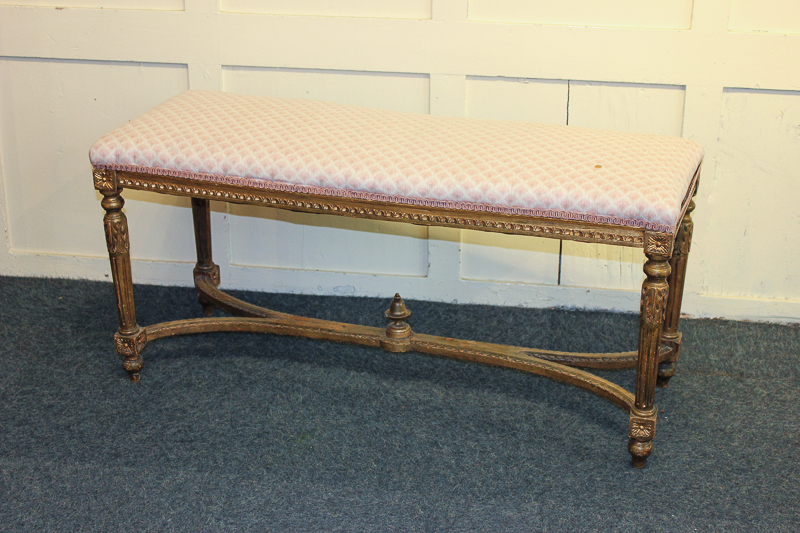 A 19th century giltwood stool with upholstered rectangular top, on four carved legs joined by curved