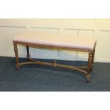 A 19th century giltwood stool with upholstered rectangular top, on four carved legs joined by curved