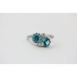 A blue zircon crossover ring claw set with two brilliant cut diamonds in 18ct white gold