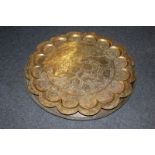 An Indian brass dish with scalloped border and engraved decoration, and two plain circular metal