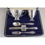 A George V cased silver christening set comprising two-handled bowl, christening mug, knife, fork,