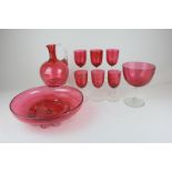 A set of six cranberry glass wine glasses, a carafe, a shallow dish and a large goblet