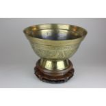 A Chinese brass bowl depicting a dragon, character mark to base, on carved hardwood stand, 29cm