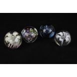 Four circular glass paperweights including one by Verrerne du Ponant and two containing flower