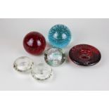 Two circular glass controlled bubble paperweights in red and blue, a clear glass and coloured