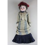 A German porcelain head and shoulder doll with padded leather body, legs and arms and porcelain