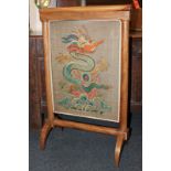 A 19th century mahogany fire screen with brass mounts and tapestry screen decorated with a dragon,