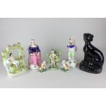 Seven Staffordshire pottery figures including a black dog, two cats and a Cupid with bocage