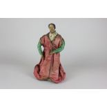 A wooden creche figure doll, possibly Italian, of a bearded man in red silk costume, on wooden