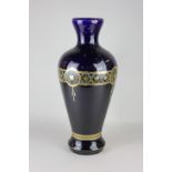 A cobalt blue glazed porcelain vase with gilt decoration of a stylized rose inside a laurel