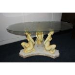 A oval glass topped coffee table the base in the form of three nude kneeling ladies