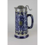 A Victorian stoneware pewter lidded jug with overlaid floral scroll decoration around central