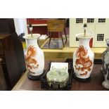 20th cent. Ceramics: Chinese lamp bases on treen stands, decorated with red oxide dragons on a cream