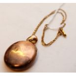 A YELLOW METAL OVAL LOCKET ON FINE CHAIN
