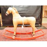 A VINTAGE STRAW-FILLED ROCKING HORSE WITH HAIR MANE AND TAIL ON A RED PAINTED ROCKING BASE,