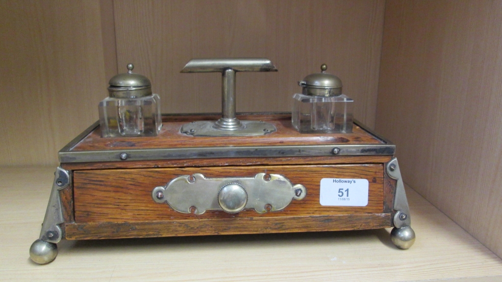 An Edwardian oak and white metal mounted desk stand, with two wells, pen rest and drawer on ball