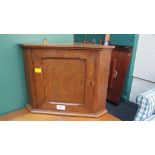 A small oak wall mounting corner cupboard with panelled door