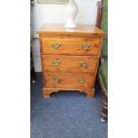 A small yew wood chest of three drawers, with brass drop handles on bracket feet