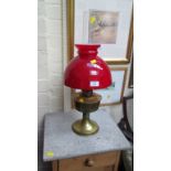 An Edwardian brass paraffin lamp, with red glass diffuser