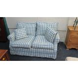 A contemporary two person settee, upholstered in green/blue check, with matching scatter cushions