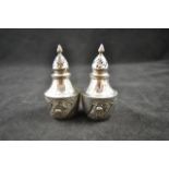 A pair of Victorian silver pepperettes with embossed decoration and flambeau finials, London 1890,