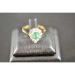 An 18ct gold ring with pear shaped emerald surrounded by eleven diamonds, emerald approx .75pts -