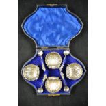 A cased set of four silver shell pattern salts with apostle salt spoons, Birmingham 1877, maker H&