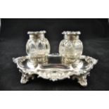 A Victorian embossed silver oval inkstand, foliate design with scroll feet, two glass bottles,