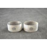 A cased pair of engine turned oval silver napkin rings, Birmingham 1925, maker F B Bros. - approx