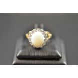 A 9ct gold ring with central opal surrounded by diamonds in cluster setting, size P1/2. CONDITION