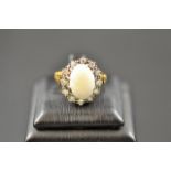 An 18ct gold ring with scroll detail to shoulders, set with central opal surrounded by twelve