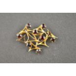 A 9ct gold brooch set with eight garnets in abstract interlinked triangular design - total gross