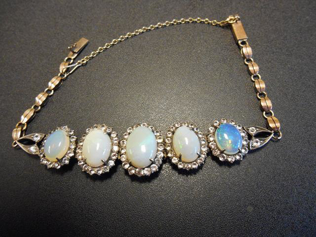 An opal and white sapphire panel bracelet, with five graduated opals surrounded by white sapphires