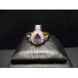 A 9ct gold ring set with a pear shaped sapphire surrounded by diamonds,