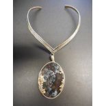 A handcrafted silver mounted agate pendant suspended on silver collar