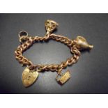A 9ct gold curb link charm bracelet with padlock clasp and four charms - approx gross weight 60g