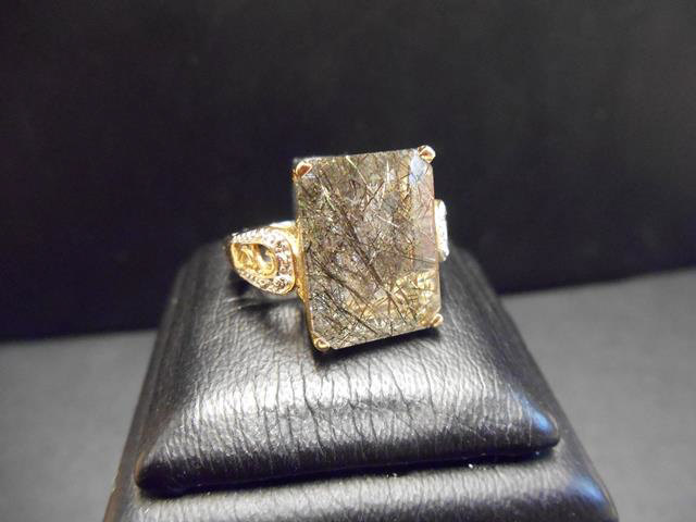 A 9ct gold ring set with an emerald cut rutilated quartz in a filigree setting with diamond