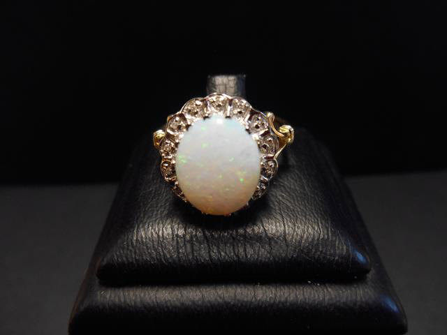 A 9ct gold ring set with a central opal surrounded by diamonds,
