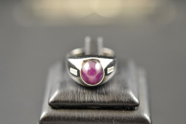 A 14k white gold ring, set with cabouchon star ruby flanked to either side with a diamond - size