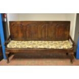 An eighteenth century oak settle with four panels to back, scroll arms, metal mesh seat and cabriole