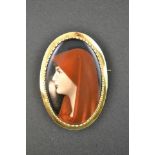 A gold brooch mounted with hand painted porcelain plaque depicting girl in red headscarf, 'pie-