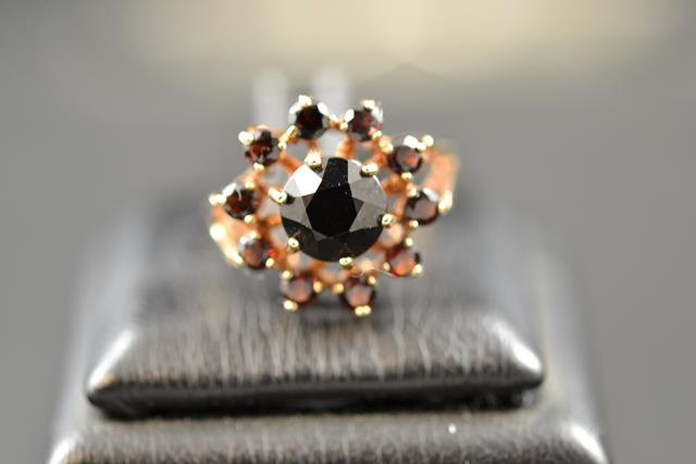 A 9ct gold ring with central garnet surrounded by ten smaller garnets in floral setting - size P.