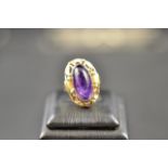A 14k yellow gold German handmade ring set with oval cabochon cut amethyst, with rose gold