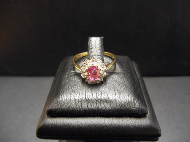 An 18ct gold ring with a pink sapphire surrounded by diamonds in a floral setting, size M - approx