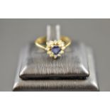 An 18ct gold ring set with heart shaped sapphire surrounded by twelve diamonds -  size J 1/2.