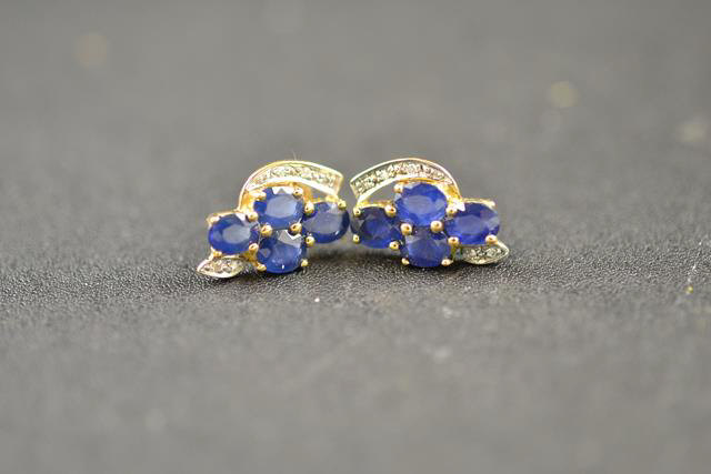 A pair of 9ct gold stud earrings of abstract design, each mounted with four sapphires and five small