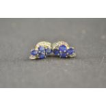 A pair of 9ct gold stud earrings of abstract design, each mounted with four sapphires and five small